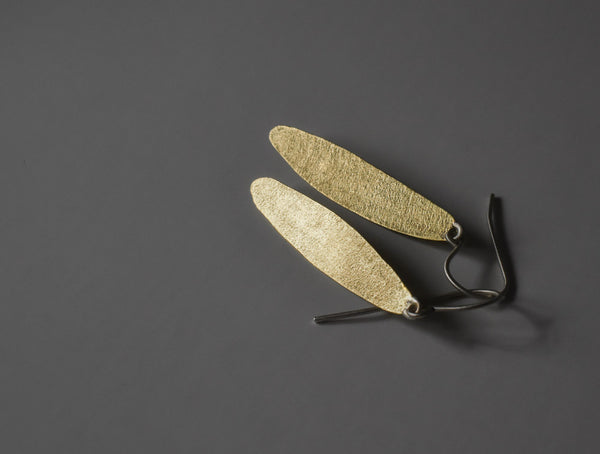 angle view of hand made simple leaf brass earrings with sterling silver ear wires