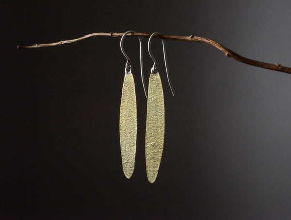 view of simple leaf brass textured earrings hanging